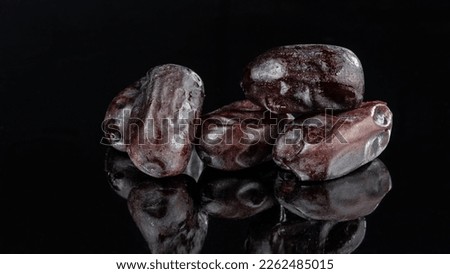 A few dried dates on a dark mirror background. Selective focus.