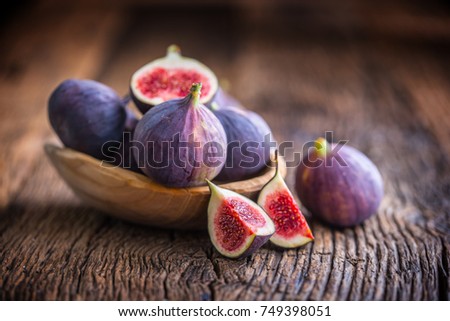 A few figs in a bowl on an old wooden background.