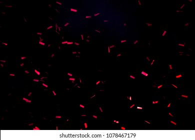 A Few Red Confetti Fired On Air During A Festival At Night. Image Ideal For Backgrounds. Black Sky As Background. Confetti Illuminated By Lights
