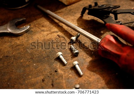 A few screws, a screwdriver, a locking ring picker, a key on a dirty table