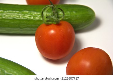 A few tomatoes and cucumbers. Tomato with water drops. On a white background. Macro.