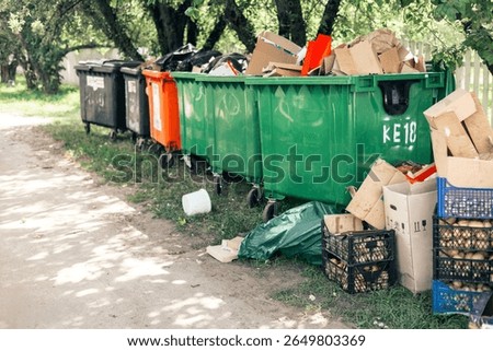 Few trashcans full of garbage, standing over trees