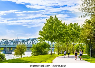 Few women running and cycling in beautiful green park alongside the river.Shot at Danube island,capital city of Austria - Vienna.The best place for sport activity and healthcare in this european town.