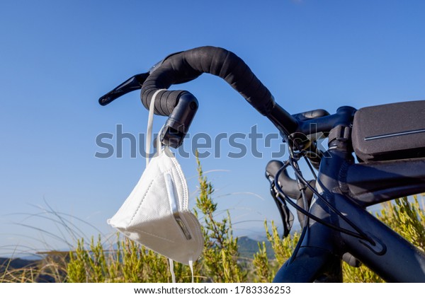 FFP2 mask hanging from the handlebar of a bicycle, cyclists protect themselves when doing sports. FFP2 mask hanging from the handlebar of a bicycle, cyclists protect themselves when doing sports.