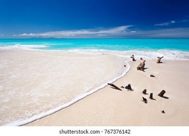 Ffryes Beach In Antigua With Driftwood And A Wave, The Active Montserrat Volcano On The Horizon.