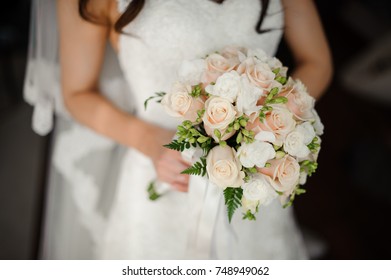 Fiancee in a beautiful white dress holding a beautiful bouquet of wedding flowers made of tender roses in hand