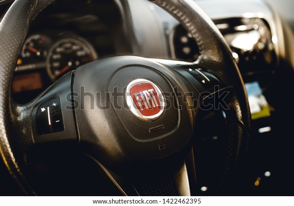 \
Fiat, cars, brands. Photo of the interior of a\
car Fiat Pálio Weekend 1.8 model 2016. Highlight the vehicle\
steering wheel with a company logo. Brasília, Federal District -\
Brazil. June, 11, 2019.