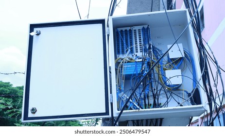 Fiber optic box on pole. Close-up of damaged optical fiber cable splitter box and cable inside with connector of internet system in urban community. Selective focus