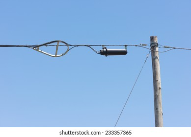 Fiber optic splice enclosure and cable storage bracket hanging on aerial messenger strand bonded to a wood pole