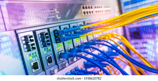 Fiber Optical cables connected to an optic ports and Network cables connected to ethernet ports - Shutterstock ID 1938620782