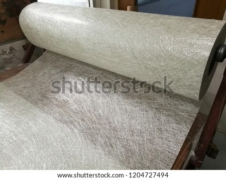 Fiberglass chop strand mat roll on the table is in process for prepare raw material in FRP production