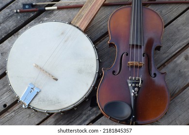 Fiddle And Banjo. Fretless Clawhammer Banjo With Fiddle And Bow On A Wooden Table. Used Mostly For Old-time Music From The Appalachian Region Of The United States.