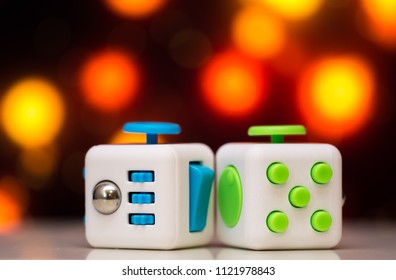 Fidget cube antis stress toy. Detail of finger play toy used for relax. Gadget placed on colorful bokeh background.