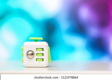 Fidget cube antis stress toy. Detail of finger play toy used for relax. Gadget placed on colorful bokeh background.