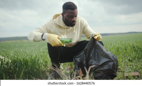 In The Field African American Man Volunteer Gathering Plastic Bottles In Garbage Bag Ecology Nature Pollution Rubbish Care Charity Volunteering Community Environment Young Altruism Recycle Slow Motion