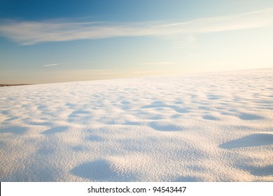 The Field Covered With Snow In A Winter Season. A Sunny Day. The Field All Is Covered By High Snowdrifts