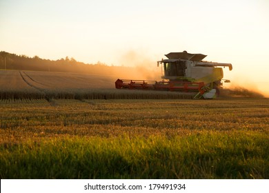 A field getting harvested by a agricultural machine.