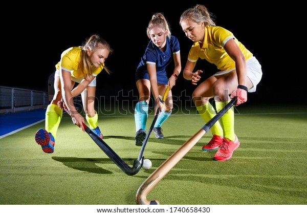 Field hockey female players struggle for the\
ball. Concept image hockey team\
game