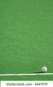 A field hockey pitch made from artificial turf with a ball.