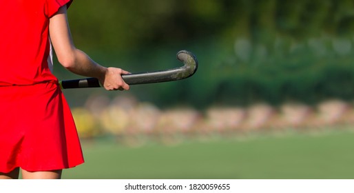 Field hockey player, in possesion of the ball, running over an astroturf pitch, looking for a team mate to pass to. Team sport concept