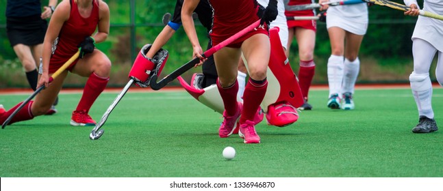 Field hockey players challenge eachother for possession of the ball on the midfield battle of a hockey mach
