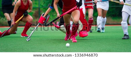 Field hockey players challenge eachother for possession of the ball on the midfield battle of a hockey mach
