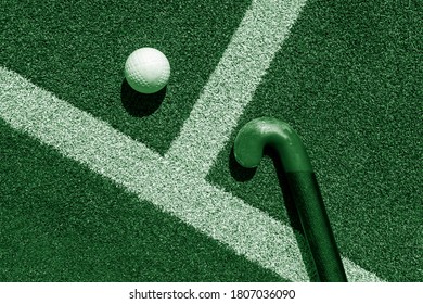 Field hockey stick and ball on grass. Green color filter