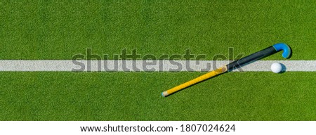 Field hockey stick and ball on green grass. Team sport concept