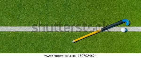 Field hockey stick and ball on green grass. Team\
sport concept