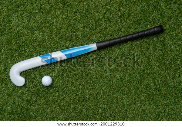 Field hockey stick and ball on the green field.\
Professional sport\
concept
