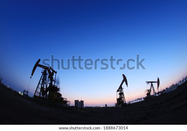In the\
field, the oil pump in the evening, the evening silhouette of the\
pumping unit, the silhouette of the oil\
pump
