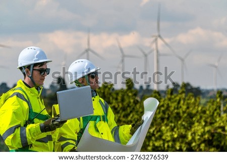Field project managers synchronizing operational schedules via smartwatch at industrial construction site. Civil engineers executing logistics planning for energy infrastructure.
