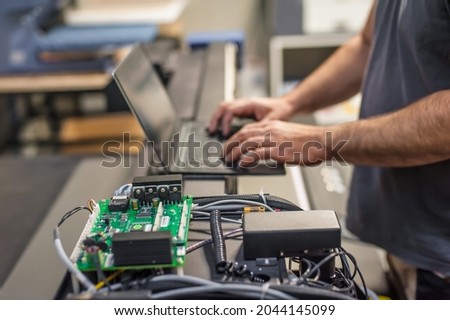 Field service maintenance engineer technician electrician inspect and control machine hardware and software system with laptop computer. Electric installation