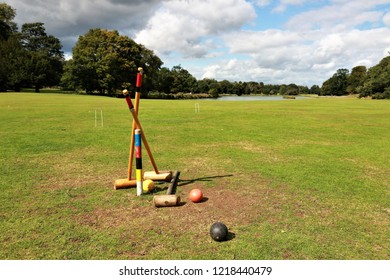 Field trees and cloudy blue sky featuring a croquet set and balls unattended as if left behind after a game