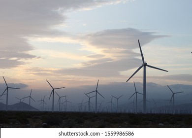 A field of windmills spin in front of a colorful sky 4199
