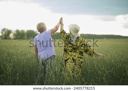 In the field, the women's shared high five becomes a symbol of their lifelong bond; their backdrop, the endless sky.