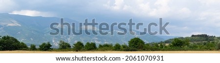 Fields and forests of Bulgaria before the rain. Panorama. Thunderhead covers the Balkans. Downpour is approaching agricultural land.