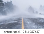 Fierce blizzard covers a strip of road with snow. Winter road conditions.