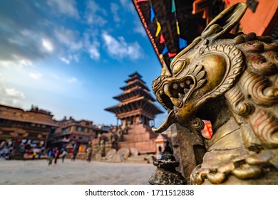 Fierce golden dragon statue looking at a tall multi storey ancient historic Nyatapola temple of Bhaktapur Durbar Square, Nepal. Ultra Wide angle looking up.