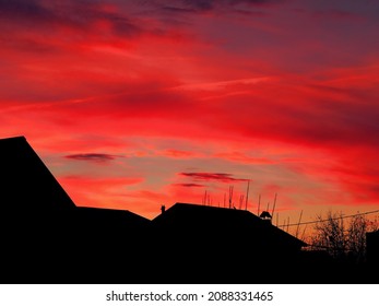 The fiery color of dramatic clouds and skies before sunrise, foreshadowing windy cold weather. Exotic skies over residential buildings in the fall before dawn. - Shutterstock ID 2088331465
