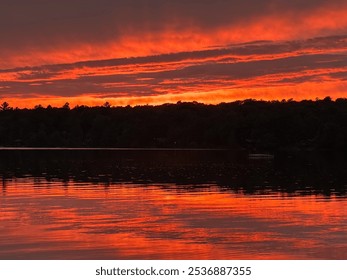 Fiery Sunset Over a Calm Lake with Dramatic Sky Reflections and Silhouetted Trees - Powered by Shutterstock