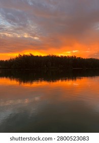 Fiery Sunset Reflection Over a Calm Forest Lake