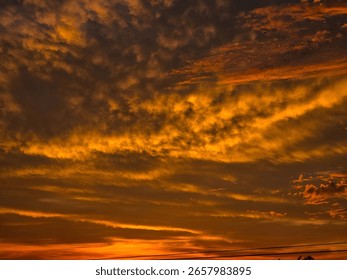 Fiery sunset sky with dramatic clouds and silhouetted horizon