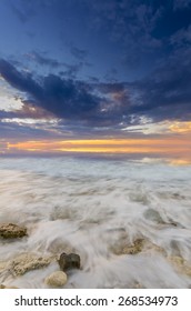 a fiery sunset and the waves lapping on the rocky shore