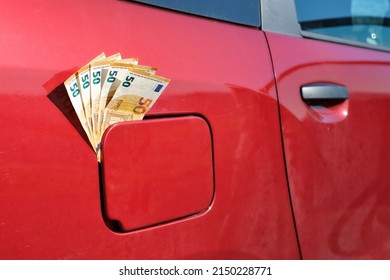 Fifty euro notes sticking out of a car's closed fuel tank, raising fuel price  - Shutterstock ID 2150228771