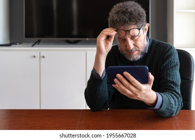 A Fifty Year Old Visually Impaired Man Takes Off His Glasses To Get A Closer Look At His Smart Phone. Poor Sight, Presbyopia, Myopia