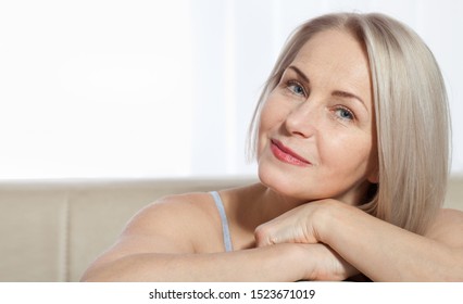 Fifty year old woman is very pleased with her well-groomed face. Plastic surgery and collagen injections. Macro face. Selective focus on face. Realistic images with their own imperfections.