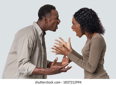 Fight During Isolation. Angry Black Man And Woman Shouting At Each Other Over Grey Studio Background. Closeup Of African American Couple Fighting, Looking At Each Other And Yelling, Profile View