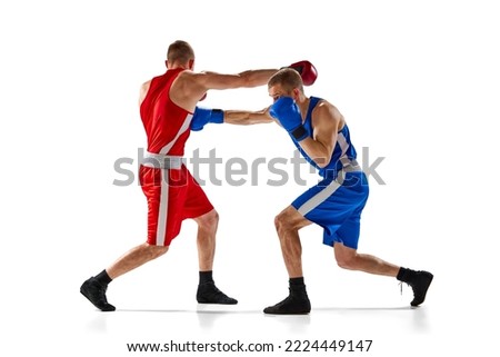 Fight. Dynamic portrait of two professional boxer in sports uniform boxing isolated on white background. Concept of sport, competition, training, energy. Copy space for ad, text