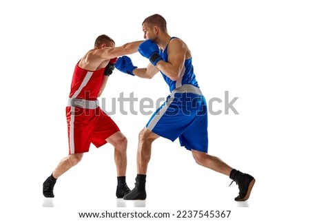 Fight. Dynamic portrait of two professional boxer in sports uniform boxing isolated on white background. Concept of sport, competition, training, energy. Copy space for ad, text